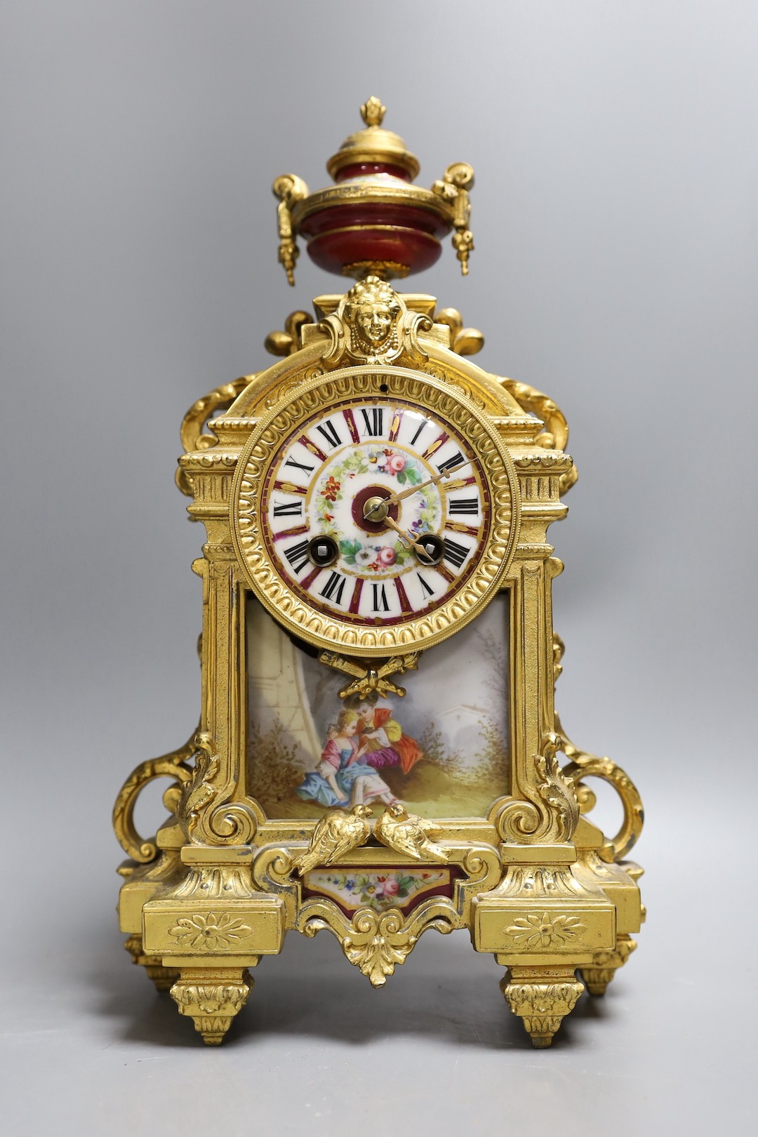A French gilt spelter mantel clock, with porcelain figurative cartouche and enamelled dial, 37 cms high.